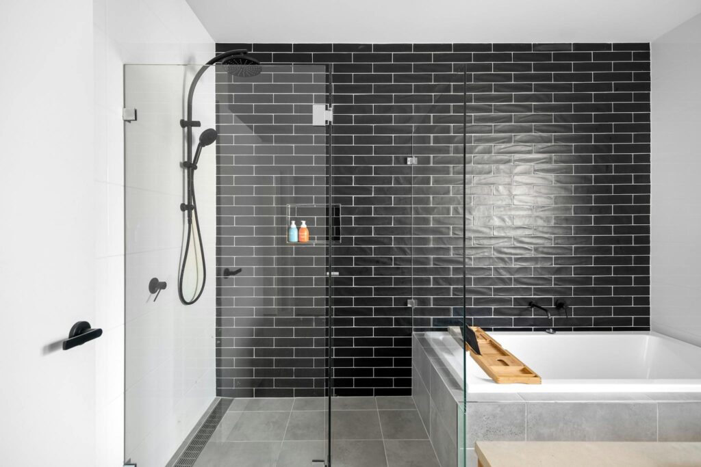 Sleek and modern bathroom featuring a black tiled wall and glass shower enclosure.